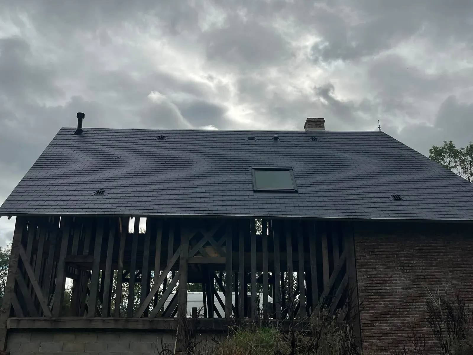 Toiture en ardoises naturelles avec fenêtre de toit au-dessus d'une façade à colombages, couvreur à Mézidon-Canon