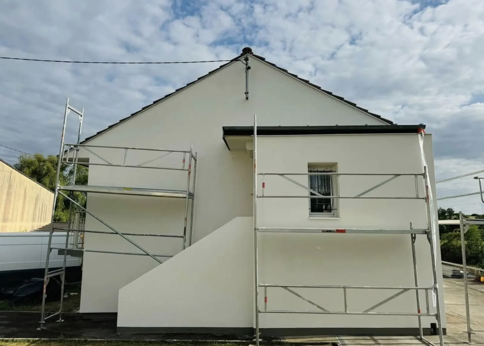 Pignon d'une maison après ravalement, façade enduite blanche avec échafaudage de pied, couvreur à Mézidon-Canon