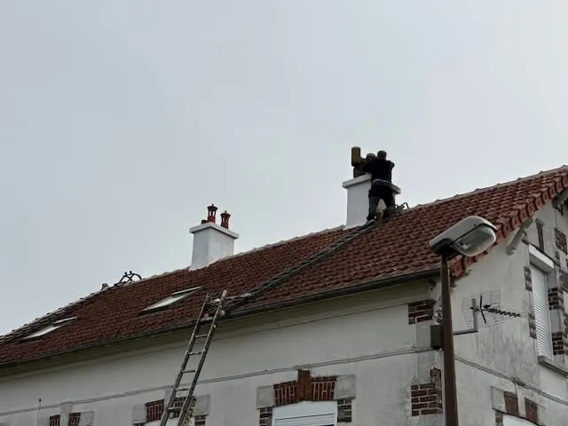 Couvreur sur une toiture en tuiles à proximité de souches de cheminée, couvreur à Orbec