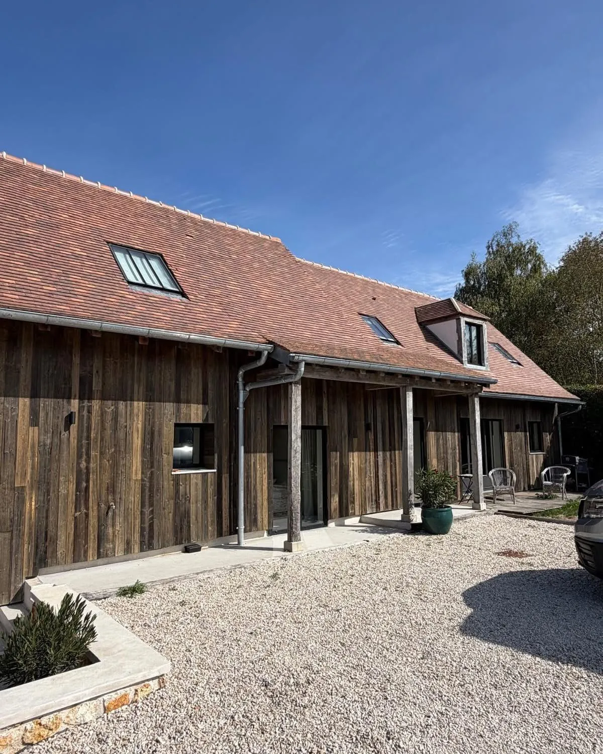Toiture en tuiles plates terre cuite avec fenêtres de toit et gouttières zinc sur une maison en bardage bois, couvreur à Argences